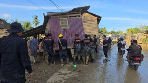 Bahu Membahu Memindahkan Rumah Terseret Banjir yang Melintang di Jalan Nasional