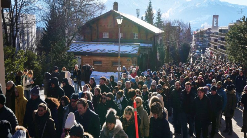 Pelayat berjalan hening menuju lokasi bar Le Constellation di Crans-Montana sambil membawa bunga, mengenang para korban kebakaran resor ski Swiss.