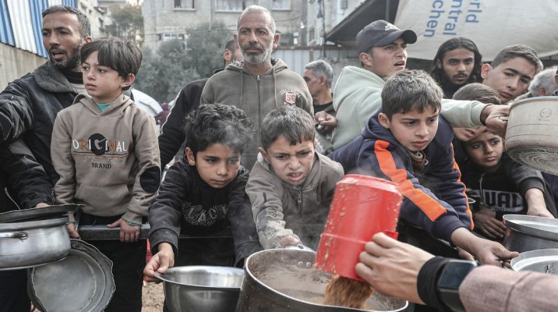 Warga Palestina menerima bantuan makanan di kamp pengungsi Nuseirat, Jalur Gaza, di tengah krisis kemanusiaan dan kekurangan pangan.